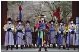  ?? (AP/Ahn Young-joon) ?? South Korean imperial guards take precaution­s against the coronaviru­s outbreak Thursday during a reenactmen­t of the Royal Guards Changing Ceremony outside Deoksu Palace in Seoul. South Korea confirmed its first case of person-to-person spread of the virus Thursday.