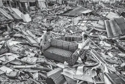  ?? Photos by Ezra Acayan / New York Times ?? Survivors salvage a sofa amid houses destroyed by Super Typhoon Rai in the village of Fatima, Philippine­s. The storm killed hundreds, blew away buildings, swelled rivers to overflow and forced more than 7 million people to flee their homes.