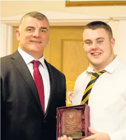  ??  ?? Prop Thomas Harper receives the Most Improved 1st XV Forward award from Rowland Phillips