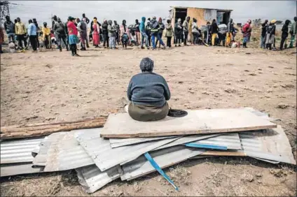  ?? ?? Settled: An woman sits on her building materials waiting for her children to be taken to select a piece of land.