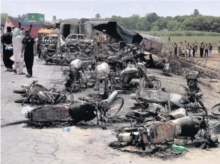  ?? Iram Asim ?? > Pakistan army soldiers stand guard while rescue workers yesterday examine the site of an oil tanker explosion at a highway near Bahawalpur, Pakistan