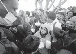  ?? GREGORY BULL/AP ?? People seeking asylum into the United States are given food as they wait for news of policy changes Friday in Tijuana, Mexico, just over the border from San Diego.