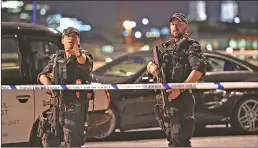  ?? Associated Press photos ?? Armed police officers stand guard on London Bridge in central London, Saturday. British police said they were dealing with "incidents" on London Bridge and nearby Borough Market in the heart of the British capital, as witnesses reported a vehicle...