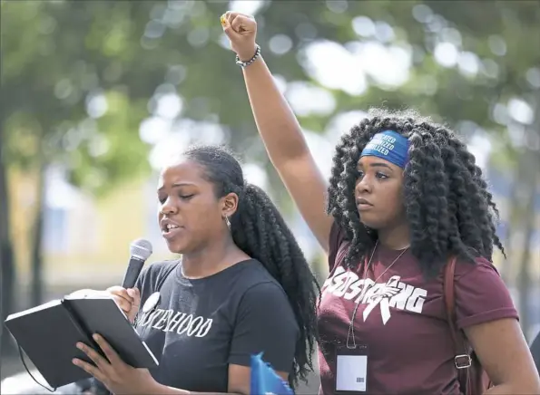  ?? Jessie Wardarski/Post-Gazette photos ?? Stoneman Douglas High School shooting survivor Mei-Ling Ho-Shin, 17, right, stands with her fist raised high behind 18-year-old Nia Arrington, a Pittsburgh CAPA graduate, as she recites a message Saturday to a large audience of teachers, educators and community members Downtown.