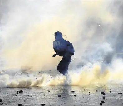  ?? CLAUDIO SANTANA / GETTY ?? Un manifestan­te en medio del humo en una de las protestas del pasado viernes.