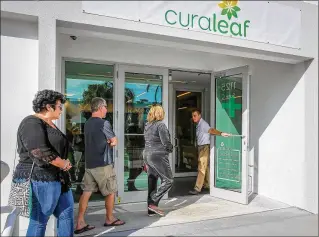  ?? DAMON HIGGINS / THE PALM BEACH POST ?? A worker at Curaleaf in Lake Worth opens the door Monday morning to a line of people waiting to get into the city’s second medical marijuana dispensary.