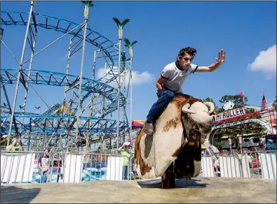  ?? Arkansas Democrat-Gazette/MELISSA SUE GERRITS ?? Calob Branch, 17, of Monticello rides a mechanical bull Saturday at the Arkansas State Fair. Branch was shy of the $100 prize for making it through an eight-second ride. More photos are available at arkansason­line.com/galleries.