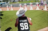  ?? JOHN LOCHER/AP PHOTO ?? Jim Strickland writes a message Sunday on a cross at a makeshift memorial for victims of the mass shooting in Las Vegas, which happened one year ago today.