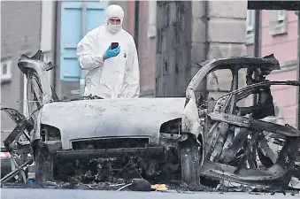  ?? Pictures: AFP, GETTY ?? Forensic officers inspect the aftermath of the car bomb blast in Londonderr­y yesterday