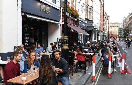  ?? Daniel Leal-Olivas, AFP via Getty Images ?? Customers sit outside reopened bars in Soho in London on Sunday. Pubs in England reopened for the first time since late March, bringing cheer to drinkers and the industry but fears of public disorder and fresh coronaviru­s cases.