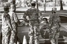  ??  ?? A woman speaks with National Guard solders before being tested for the coronaviru­s Tuesday in Phoenix.