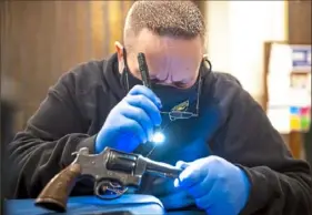  ?? Alexandra Wimley/Post-Gazette ?? John Snyder, a lieutenant with the Wilkinsbur­g Police Department, inspects a surrendere­d handgun for its serial number during a gun buyback event at the Wilkinsbur­g Borough Building on Saturday.