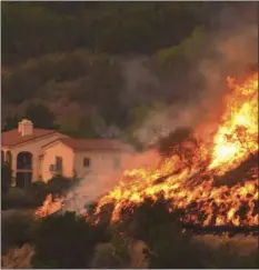  ??  ?? In this Thursday, Dec. 14, 2017, file photo provided by the Santa Barbara County Fire Department, flames from a back firing operation underway rise behind a home off Ladera Lane near Bella Vista Drive in Santa Barbara. MIKE ELIASON/SANTA BARBARA COUNTY...