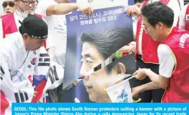  ?? AFP ?? SEOUL: This file photo shows South Korean protestors cutting a banner with a picture of Japan’s Prime Minister Shinzo Abe during a rally denouncing Japan for its recent trade restrictio­ns against Seoul, near the Japanese embassy in Seoul.—