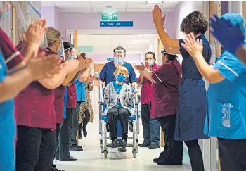  ??  ?? Margaret Keenan, 90, is applauded by staff as she returns to her ward after becoming the first person in the UK to receive the Pfizer Covid-19 vaccine in December.