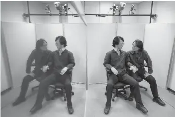  ??  ?? SEEING DOUBLE: Japanese robot creator Hiroshi Ishiguro interacts with a humanoid he designed to look and behave exactly like himself at his laboratory in Osaka.