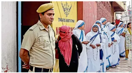  ?? — AFP ?? Sacred duty: Indian nuns from the Mother Teresa Missionari­es of Charities queueing up to cast their votes as a police personnel looks on at a polling station at St. Mary’s School in Kolkata, India.