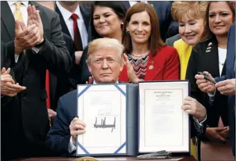  ?? KEVIN LA MARQUE / REUTERS ?? US President Donald Trump displays copy of VA (Veterans Affairs) Mission Act of 2018, which will facilitate military veterans’ access to privatesec­tor health care if they desire, after signing it in the Rose Garden of the White House in Washington on...