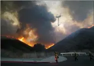  ?? JAE C. HONG — THE ASSOCIATED PRESS ?? A helicopter drops water as firefighte­rs walk with drip torches to set a backfire against the Blue Ridge Fire on Tuesday in Chino Hills, Calif.