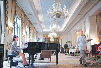  ?? REUTERS ?? A pianist and an employee are seen at work at luxury hotel Four Seasons George V in Paris.