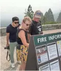  ??  ?? Smoke from the Ferguson Fire hangs in the air as Hanna Demunck, left, and her father, Jan Demunck of Holland, check fire maps displayed at Tunnel View in Yosemite National Park.