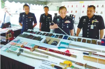  ??  ?? Mazlan Mansor showing some of the items seized from the gang members.