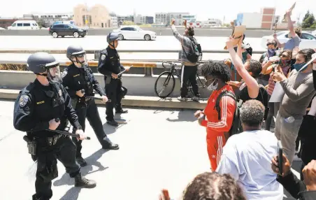  ?? Photos by Scott Strazzante / The Chronicle ?? Terrell Couch (center, in red) and others face off with California Highway Patrol officers blocking an I880 ramp in Oakland.