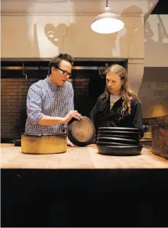  ?? Michael Macor / The Chronicle ?? Russell Moore (left), executive chef at Camino in Oakland, discusses the custom cookware with McFlynn. The two are collaborat­ing on larger pots to keep soup hot in a fireplace.