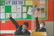  ?? (File Photo/AP/Kirsty Wiggleswor­th) ?? Students Henry Holness (left) and Eddie Favell raise their hands in class during their first day in September at Kingsdale Foundation School in London. At the time, schools in England were starting to open with special measures in place to deal with coronaviru­s.