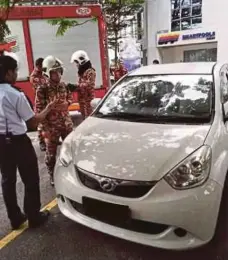  ??  ?? Firemen preparing to open the door of a car where a man was found unconsciou­s inside at Dataran Prima in Petaling Jaya yesterday.