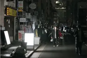  ?? KYODO NEWS VIA AP ?? People walk on a street during a black out March 17in Tokyo following an earthquake.