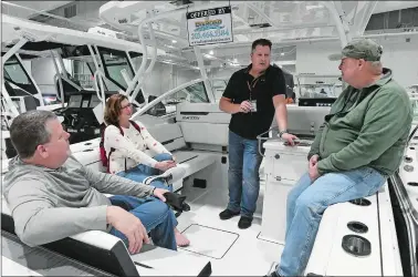  ?? DANA JENSEN/THE DAY ?? Salesman Nick DeBendet, second from right, of Diamond Marine talks with possible customers Steve Dumas, left, of Chaplin, Dee Gates, second from left, and her husband, Bob, of Ellington on Saturday while aboard a Blackfin 272 dual console boat on display at the Hartford Boat Show at Mohegan Sun. Diamond Marine is located in East Haven.