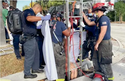  ?? TNS ?? A Delray Beach Fire Rescue crew uses a ladder and a harness to rescue a woman who had been lost in the city’s stormdrain­s.