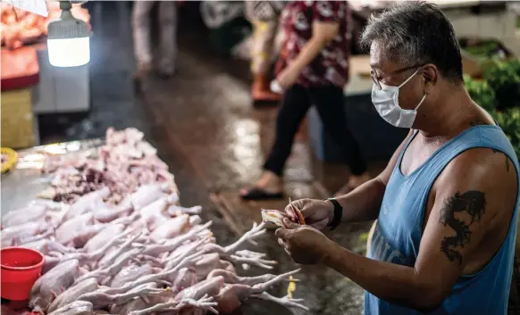  ?? AFP ?? A man prepares chickens at a market in Manila. The Philippine­s suffered its biggest quarterly contractio­n in four decades due to Covid-19 curbs