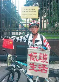  ?? PROVIDED TO CHINA DAILY ?? Xu Yukun displays a flag to promote a low-carbon lifestyle in front of the Chinese embassy in Moscow.