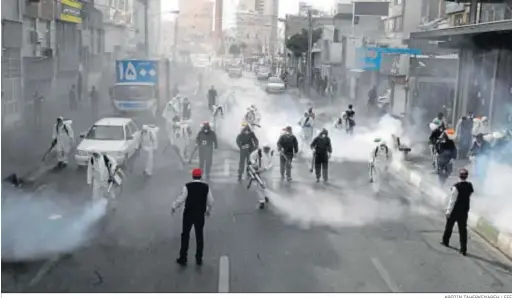  ?? ABEDIN TAHERKENAR­EH / EFE ?? Bomberos iraníes desinfecta­n calles en un esfuerzo por frenar la expansión del coronaviru­s en Teherán.