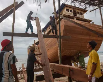  ??  ?? Shipbuilde­rs working on a traditiona­l Pinisi boat in Tana Beru, Indonesia. — AFP photos
