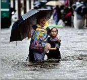  ?? PTI ?? A school girl with her guardian wades through a flooded street following heavy monsoon rains, in Mumbai, on Tuesday