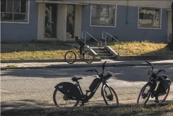  ?? Photos by Stephen Lam / The Chronicle ?? A cyclist rides past housing projects in the Sunnydale area of S.F. Reparation­s “could be more investment in education, housing and neighborho­ods,” said USF Professor James Taylor.