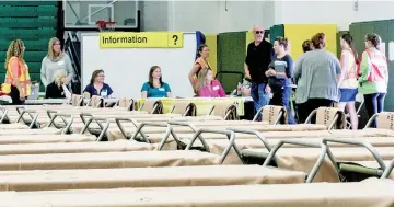  ??  ?? Volunteers listen to emergency services managers as they prepare for wildfire evacuees to arrive and start occupying the 170 cots set up in the Northen Sports Centre at the University of Northern BC in Prince George, British Columbia, Canada. — Reuters...