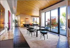  ??  ?? SLIDING GLASS doors open to a three-sided balcony that wraps the residence, which features open living areas.