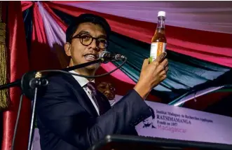  ??  ?? ABOVE: The President of Madagascar, Andry Rajoelina, holds up his “Covid Organics” cure at a launch in April. BELOW: High school students dutifully quaff bottles of the wonder-tonic doled out to them at the start of classes.