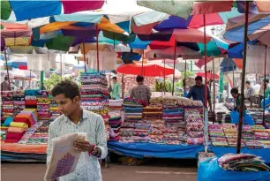  ?? — Bloomberg ?? Vendors attend to their fabric stalls at a street market in Goa.