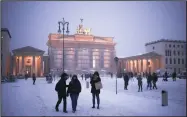  ?? (AP/Markus Schreiber) ?? People gather in front of the Brandenbur­g Gate Wednesday on a snowy winter day in Berlin, Germany.