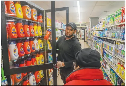  ?? ?? Leo Pichardo, left, a store associate at Gristedes supermarke­t, retrieves a container of Tide laundry soap from a locked cabinet. The stepped-up security measures tread a fine line: cutting down on shopliftin­g vs. alienating customers.