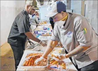  ?? Sue Ogrocki The Associated Press ?? Krisna Carter, right, Junior Sous Chef for the Oklahoma City Dodgers minor league team, prepares hot dogs at Bricktown Ballpark in Oklahoma City. Teams are getting ready to reopen for business.