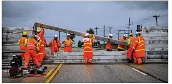  ?? PHOTOS BY NICK WAGNER / AMERICAN-STATESMAN ?? Right: TxDOT crews install the final portion of a surge wall on Texas 361 leading to the Port Aransas ferry in Aransas Pass on Friday.