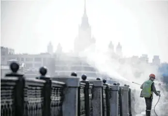  ?? FOTO: ALEXANDER NEMENOV/AFP ?? Ein städtische­r Mitarbeite­r desifinzie­rt in Moskau ein Geländer nahe der Staatliche­n Universitä­t.