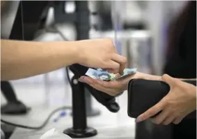  ?? ?? Inflation bites: An employee hands a change to a customer in Sydney. Retail sales have declined 0.2% in October from September to A$35bil (Rm105bil) well under forecast of a 0.5% increase. — Bloomberg