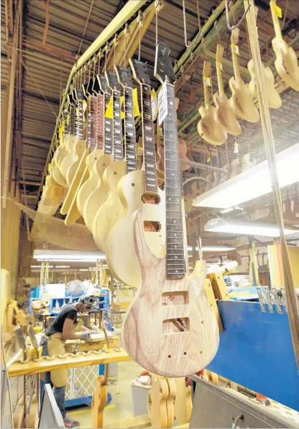  ?? Christophe­r Berkey For The Times ?? NEW GUITARS hang in the Gibson guitar manufactur­ing plant in Nashville before having more finishing work done to them.